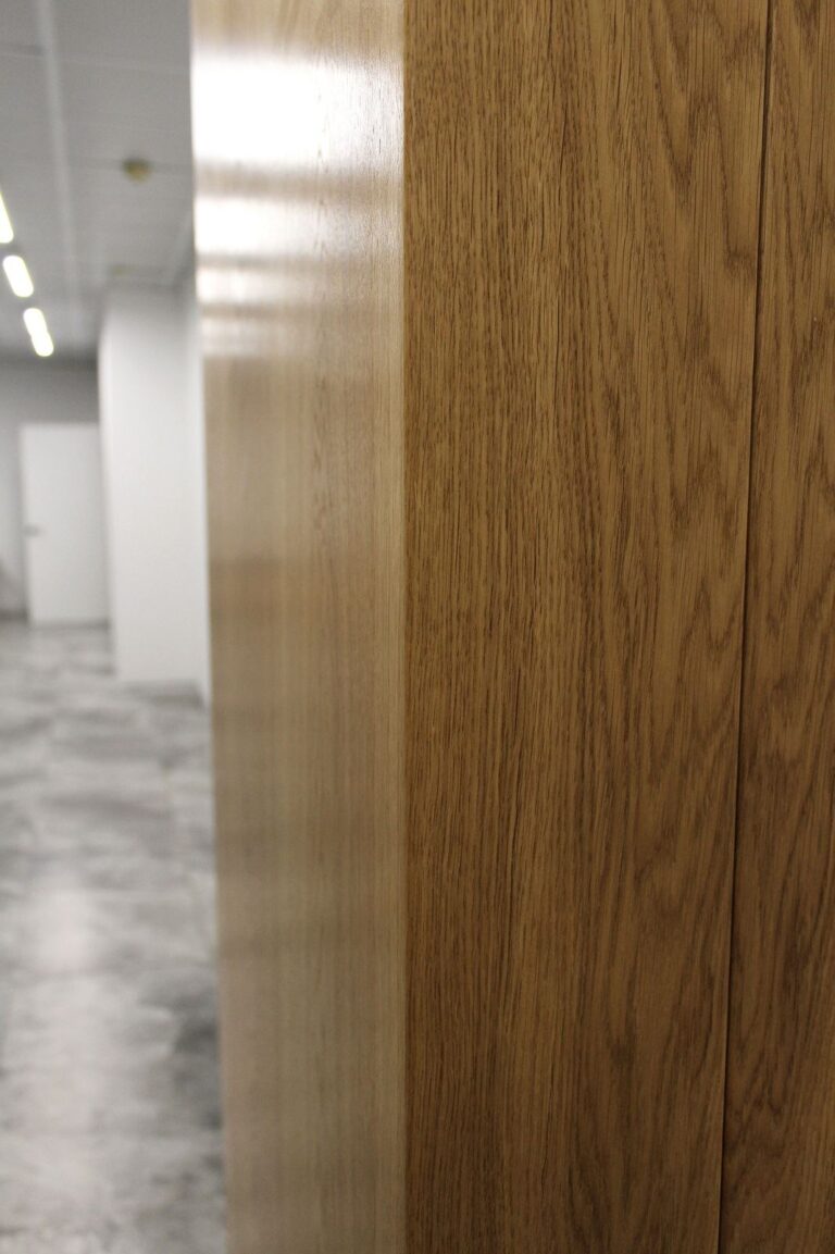Стеновые панели в шпоне дуба. Покрыты прозрачным матовым лаком. Толщина панелей 16мм., основа МДФ. Так же в проекте присутствуют распашные двери и скрытые люки. Объект – ресепшен офисного помещения.