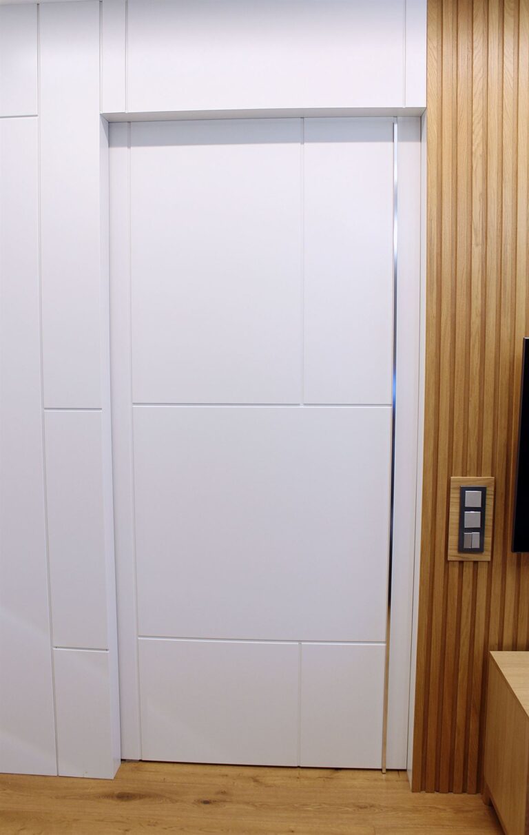 В данном проекте присутствуют стеновые реечные шпонированные панели из дуба. Покрыты матовым прозрачным лаком. Ширина ламелей 40мм, глубина 10мм, расстояние между ламелями 15мм. Изготовлена накладка под выключатели из того же шпона. Так же изготовлены панели покрытые белой эмалью и раздвижная дверь уходящая в стену.